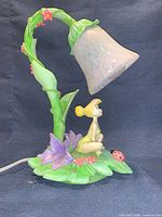 Full view of lamp showing Tinkerbell figure, vine stem, glass shade, cord