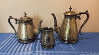 Front view of teapot, coffee pot, and creamer showing overall form and engraving