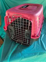 Front and top view of pink and black Petmate carrier showing door, latches and handle