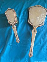 Front view of brush and mirror showing pearlescent celluloid surfaces and decorative trim