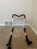 Front view of white metal bed safety rail with black foam grip and support arms