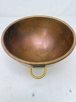 Top view of copper bowl showing interior surface and one brass handle