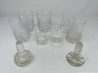 All nine pieces laid out: five tumblers, one goblet, one shot glass, two stoppers