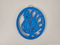 Front view of blue enameled cast iron rooster trivet