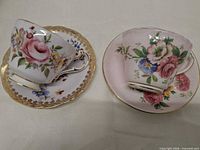 Two teacups and two saucers displaying floral pattern and gold trim