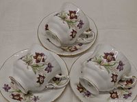 Three Paragon teacups resting on matching saucers showing floral design and gold trim
