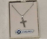 Front view of sterling cross pendant on chain inside box