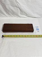 Closed wooden cigarette box beside measuring tape