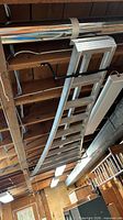 Full view of ceiling-mounted aluminum ladder in basement
