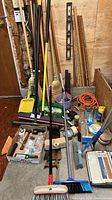 Full lot showing long-handled brooms, dustpans, level, yardsticks, brushes, extension cord and hardware