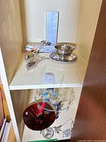 Overall view showing silver-plated bowl, tongs, and cake stand on shelf