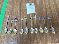 All ten souvenir spoons laid out showing crests and sizes