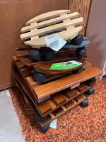 Stack of six wood plant caddies, round and square, showing swivel casters