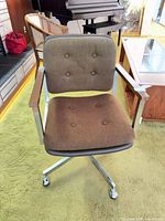 Front view showing brown fabric, button tufting, wood armrests, chrome base on casters