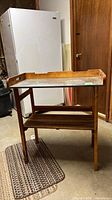 Full view of serving cart showing wood frame, metal top, lower slatted shelf
