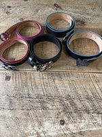 Group shot of all five belts laid flat showing colors, buckles, overall wear