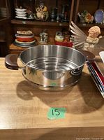 stainless steel pot with steamer insert on table