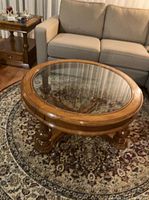 Three-quarter view of round wood and glass coffee table beside sofa