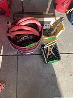 Bucket with coiled red hose beside trays of fasteners and hand tools