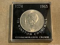 Coin in plastic case showing Churchill reverse with case text