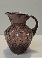 Full view of purple amethyst pressed glass pitcher showing swirl pattern and handle