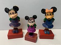 Front view of three Minnie Mouse figure sharpeners standing on red bases
