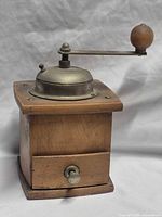 Front view showing wood box, metal top, crank and drawer