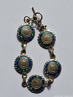 Front view of bracelet showing five Aztec medallion links with blue opal inlay and toggle clasp