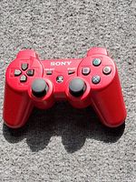 Front view of red Sony DualShock 3 controller