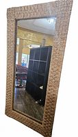 Full view of mirror showing woven frame and reflective glass
