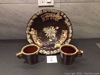 Full view of the Alpine inspired ceramic display platter bowl with two matching hefty mugs in front.