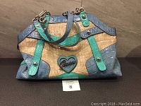 Front view of Guess ladies handbag showing multicolor patent finish with crocodile texture and heart logo metal detail on front