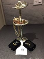 Full view of jewelry tree stand with various rings and chains, and two black velvet trays with earrings and necklaces in front.