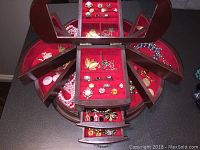 Open jewelry box with top and side compartments showing multiple rings, brooches and necklaces