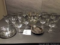 Full view of silver rimmed cocktail and wine glasses, ice bucket, snack plates and silver serving dish