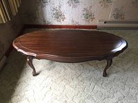 Full view of the long oval walnut coffee table showing the top and legs in natural light on carpet.