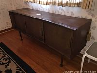 Full side angle view of walnut credenza showing curved case, sliding doors and tapered legs