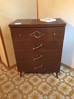Full view of the laminated walnut dresser showing front details including unique metal design on top drawer and three metal drawer pulls below.
