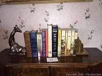 Wide shot of all books and bookends on wooden dresser surface, showing arrangement and condition.