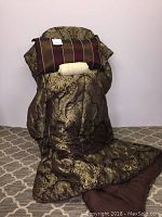 Quilt draped over chair showing gold brocade exterior and brown inside, with matching cushion on top.