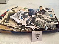 Box filled with postcards, black and white photographs, and ephemera, displayed on a table
