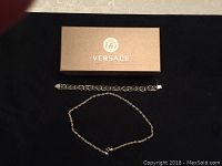Photo of the linked silver bracelet and twisted rope necklace arranged with Versace box