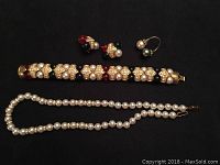 Top view of the entire jewellery lot showing pearl necklace, heavy bracelet with pearls and colorful stones, four pairs of earrings, and a pearl ring.