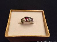 Front view of silver ring with five colored semi-precious stones displayed in a box.