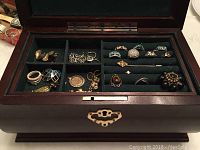 Jewelry box open showing top left compartments with chain necklaces, earrings, pendants