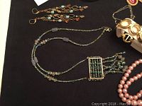 Photo showing beaded necklaces and earrings including a rectangular beaded pendant necklace and long beaded strand necklace.