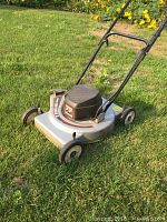 Full view of a silver and black Craftsman electric lawn mower on grass showing metal body and plastic wheels.