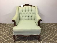 Front view showing tufted mint green upholstery, carved wood frame, and scrolled arms of Louis IV style chair.