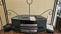 Front view showing Bose Wave Music System stacked on multi-CD changer with two remotes and accessories