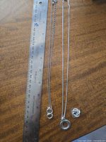 Three silver necklaces alongside ruler showing 18–20 in length